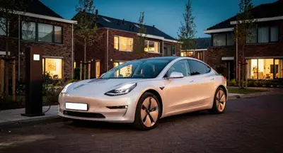 Nieuwe witte elektrische sedan bij een laadpaal in een woonstraat